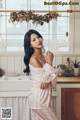 A woman standing in a kitchen next to a sink.