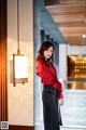 A woman in a red shirt and black skirt posing for a picture.