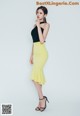 A woman in a black top and yellow skirt posing for a picture.