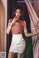A woman in a pink top and white skirt posing for a picture.