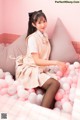 A woman sitting on top of a bed of pink and white balloons.